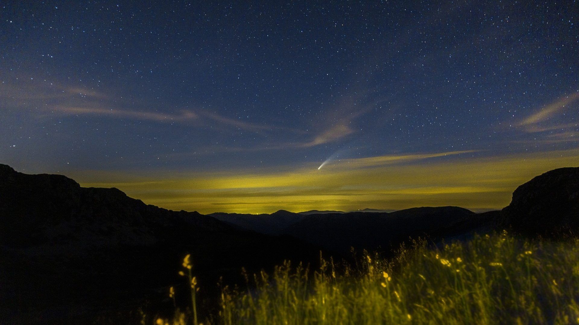 Un paisaje nocturno con estrellas y montañas.
