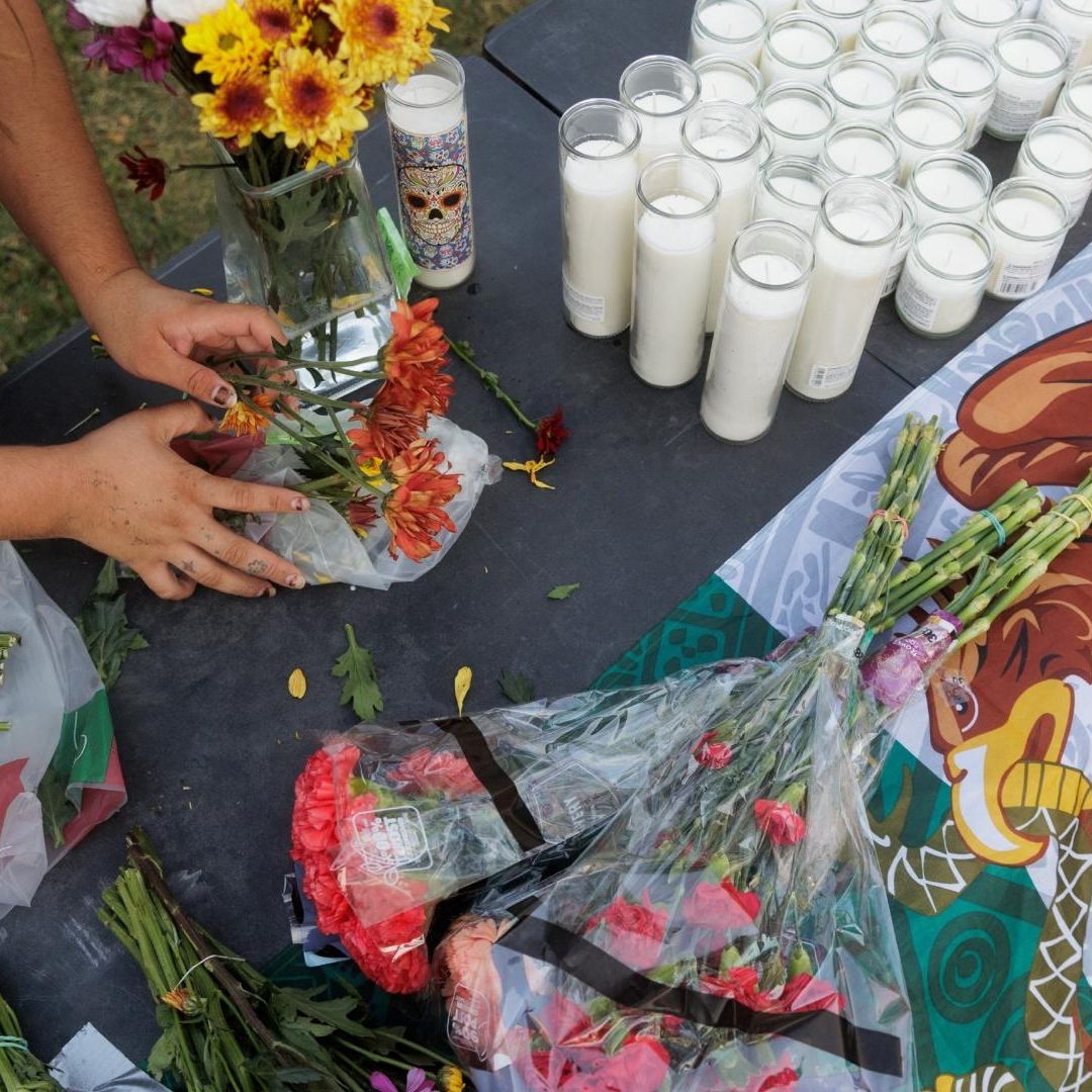 una bandera de México rodeada de flores y veladoras por mexicano que recibió disparos en sede de ICE, en Dallas