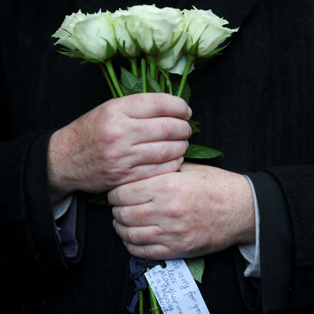 Mujer sostiene un ramo de flores blancas en señal de luto por el atentado terrorista en Manchester