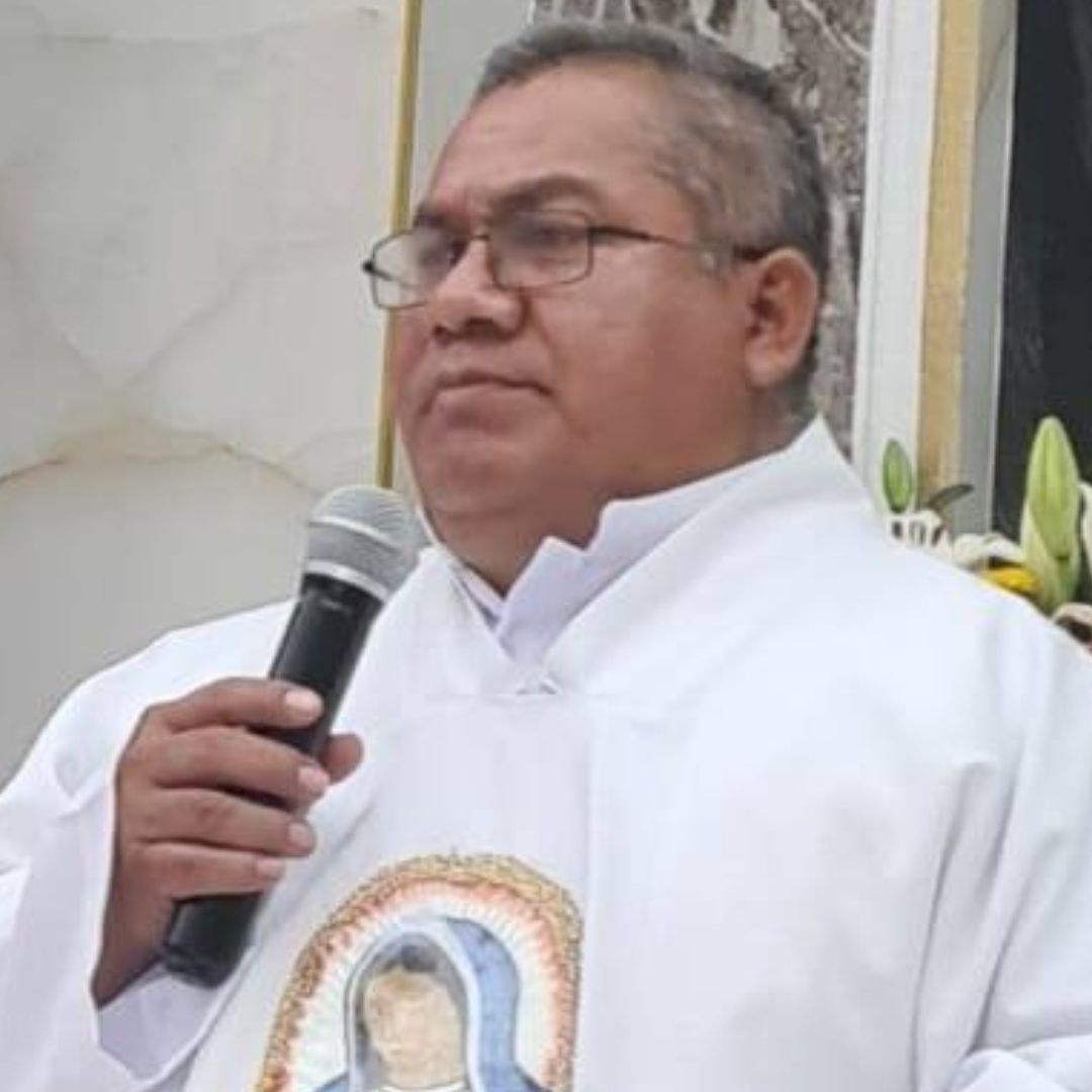 el sacerdote Bertoldo Pantaleón sostiene un micrófono