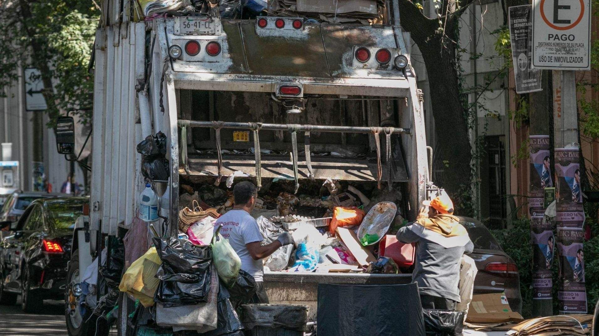 Trabajadores recolectan basura en un camión.