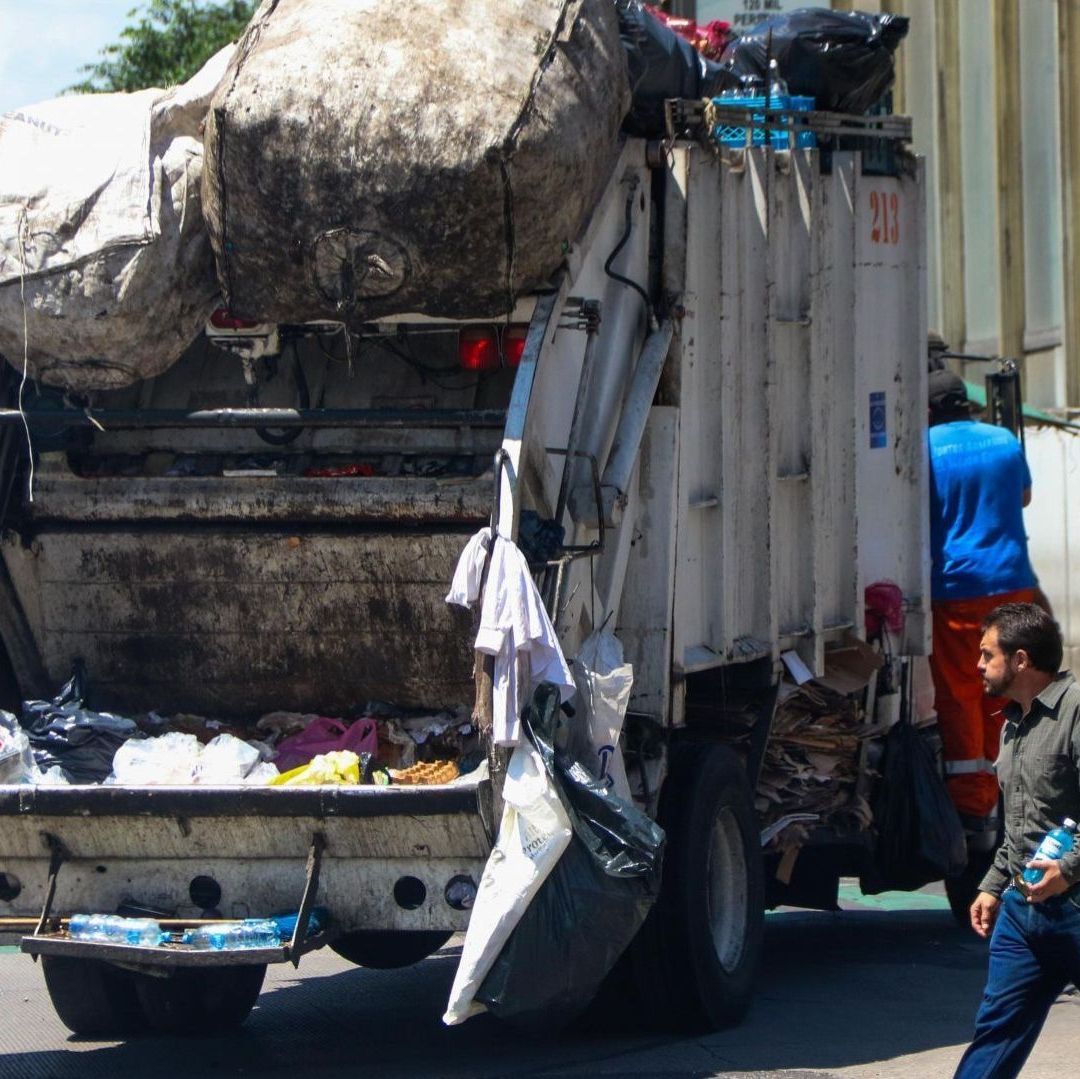 Una persona frente a un camión de basura.