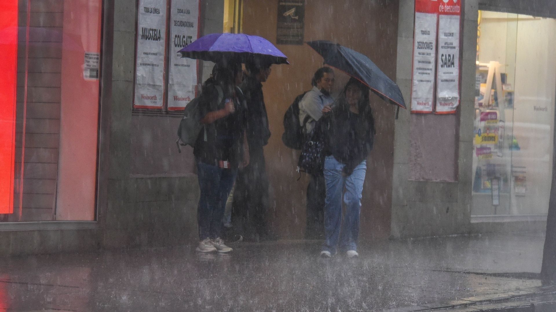 personas se resguardan bajo paraguas de la lluvia