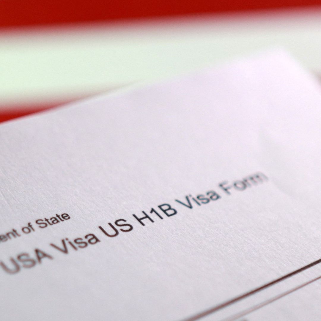 Bandera de EE. UU. y el formulario de solicitud de visa H-1B. Foto: Reuters