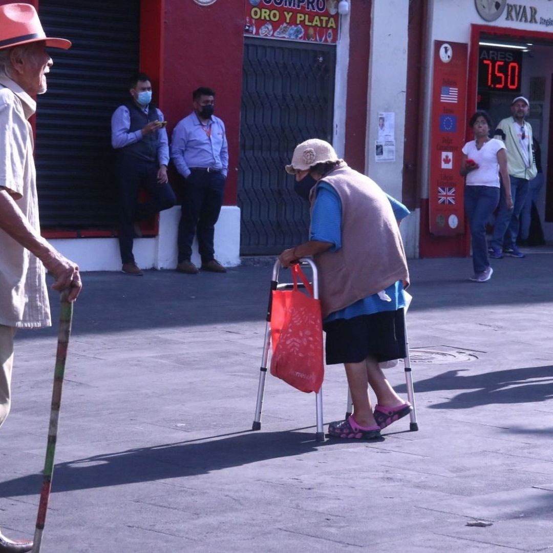 Dos adultos mayores caminan por una calle.