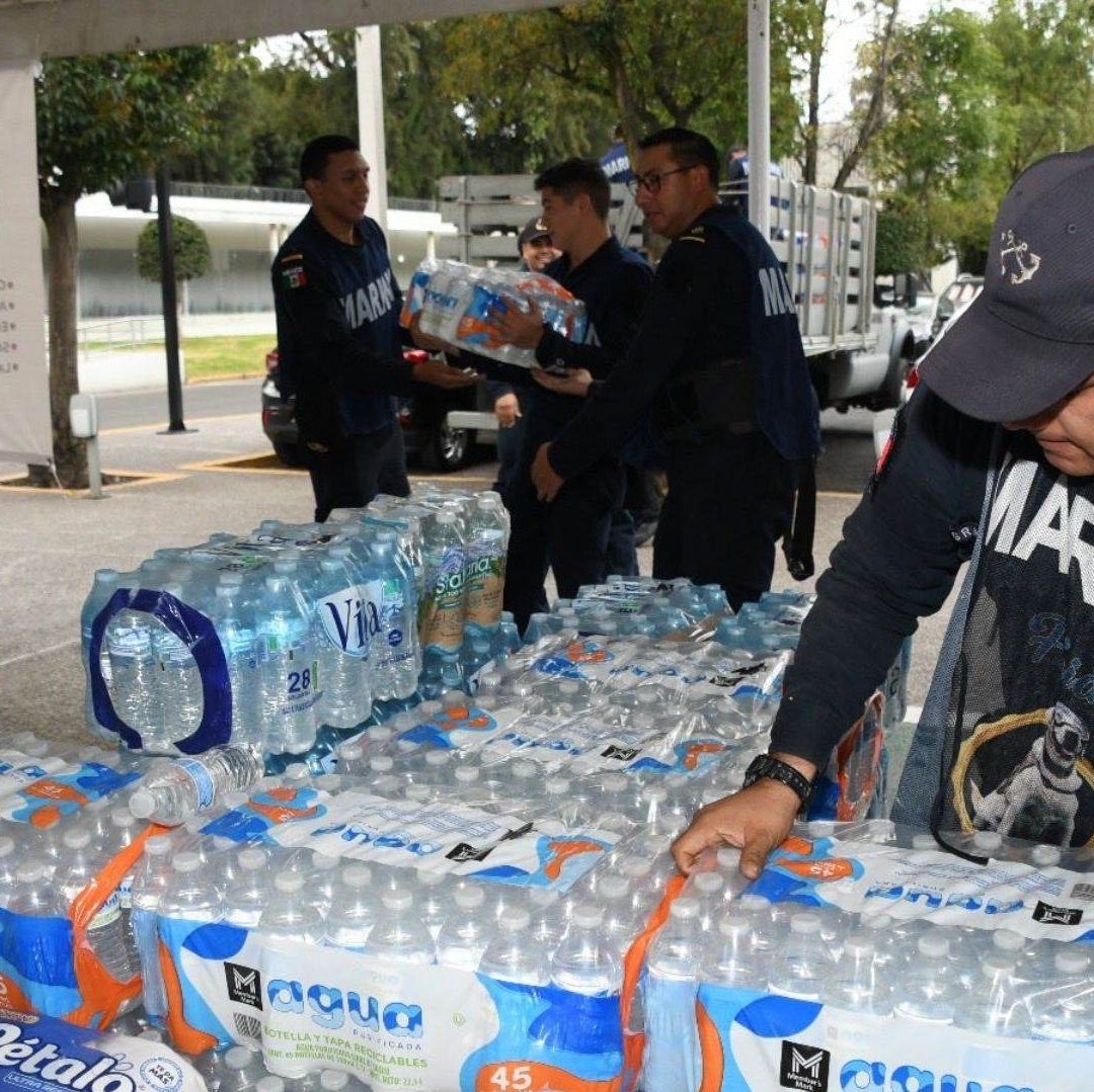 Personas cargan paquetes de agua.