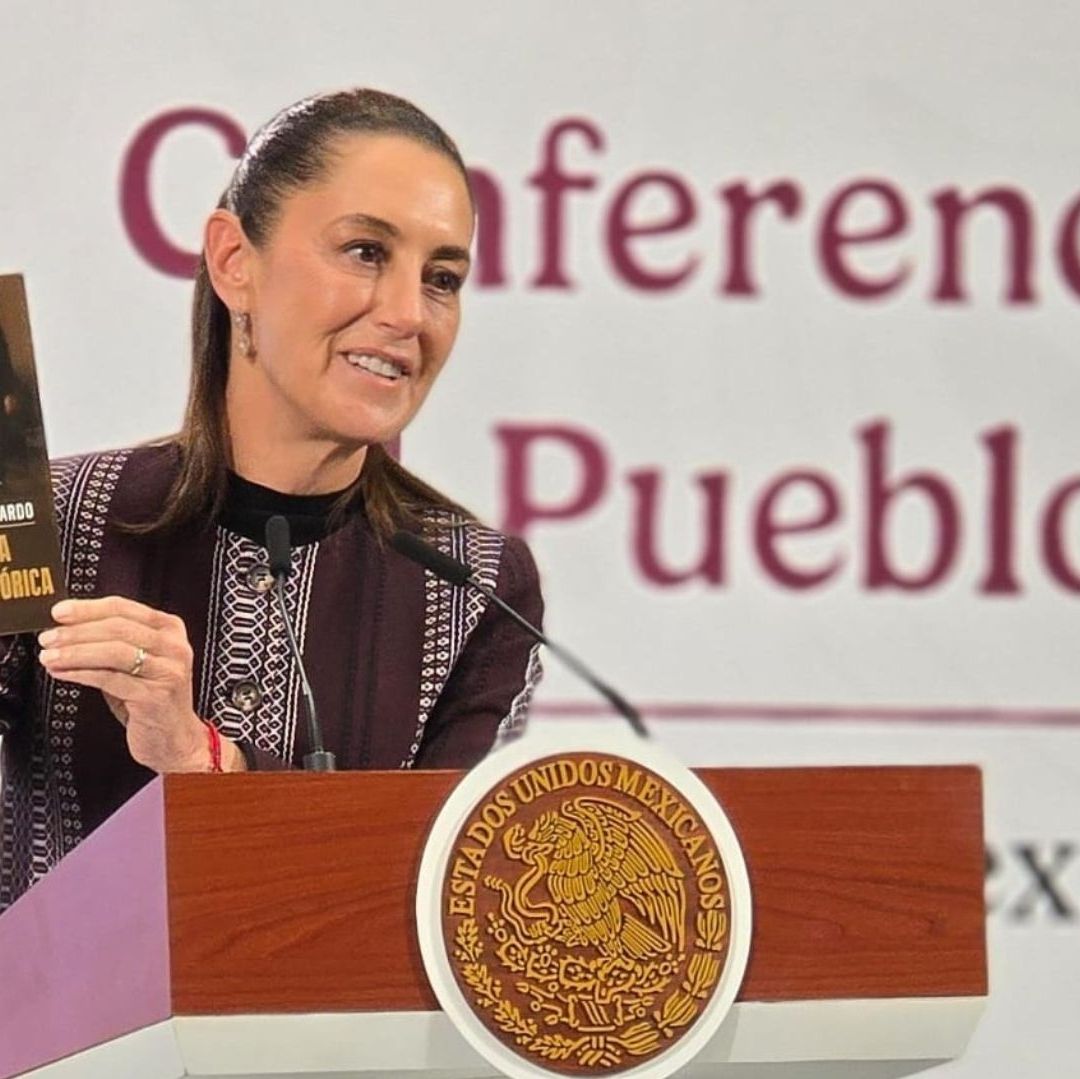 Una mujer sonriendo sostiene un libro.