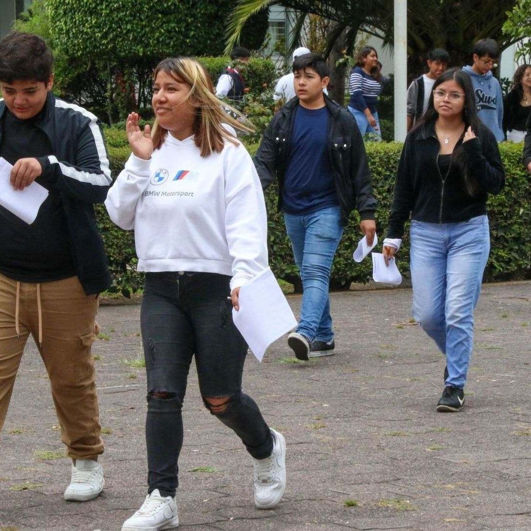Jóvenes caminan con una hoja en la mano.