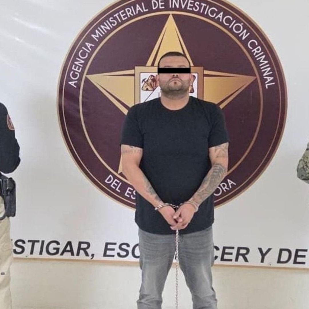 Un hombre con los ojos tapados es resgurdado por dos sujetos.