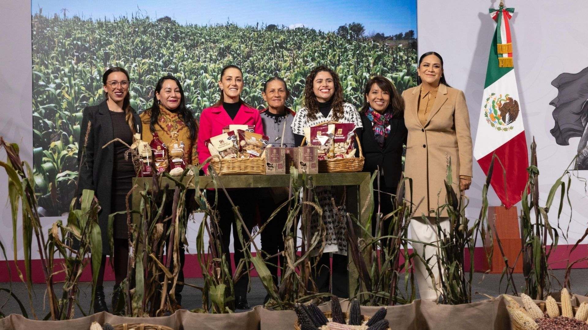 Varias mujeres posan para una foto al lado de maíz.