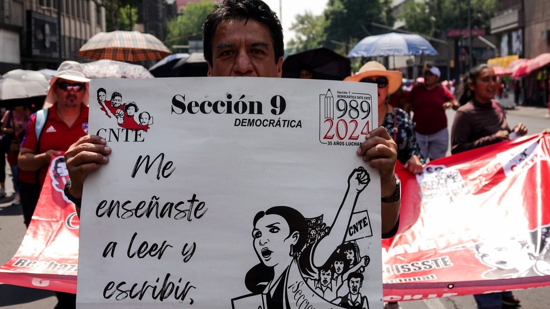 Un hombre sostiene un cártel con una mujer protestando.