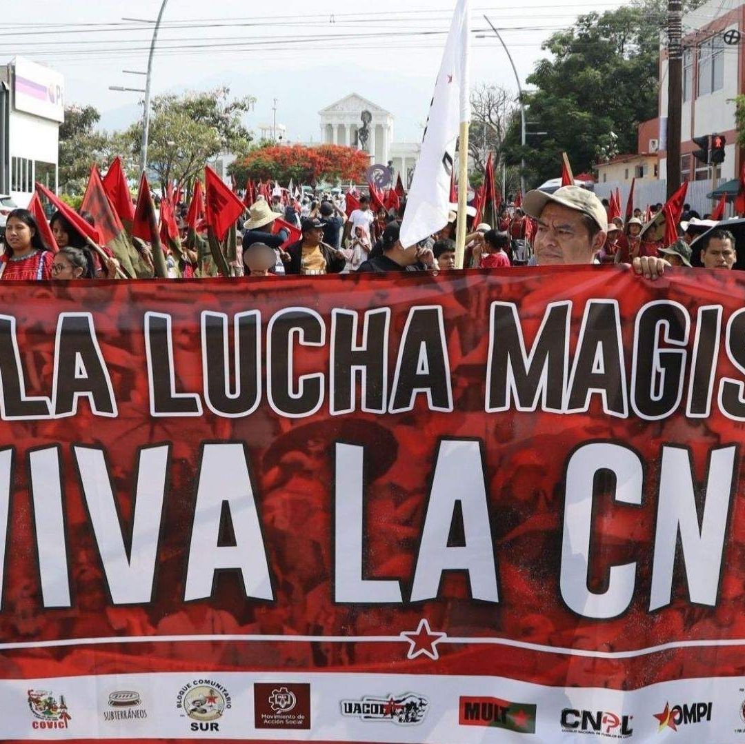 Varias personas en grupo portan un cartel .