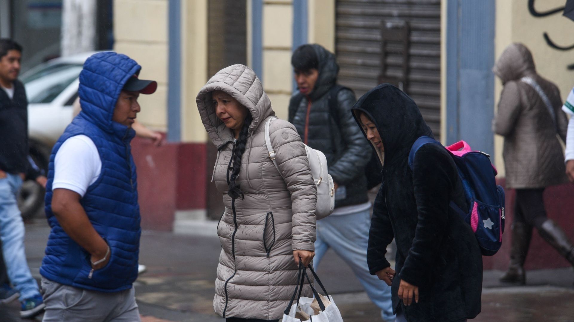 Personas abrigadas con chamarras caminan.