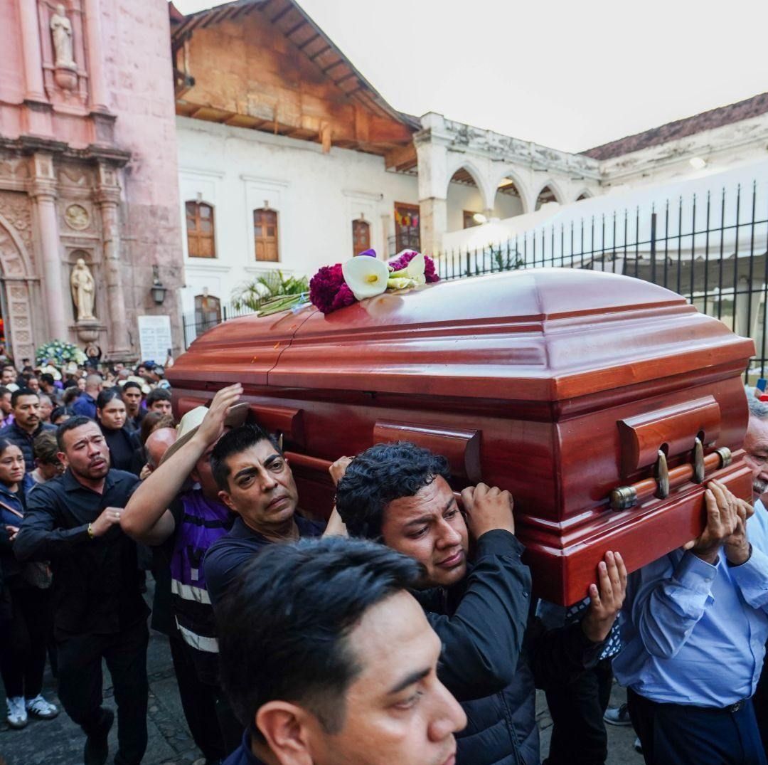 Varias personas cargan un ataúd afuera de una iglesia.