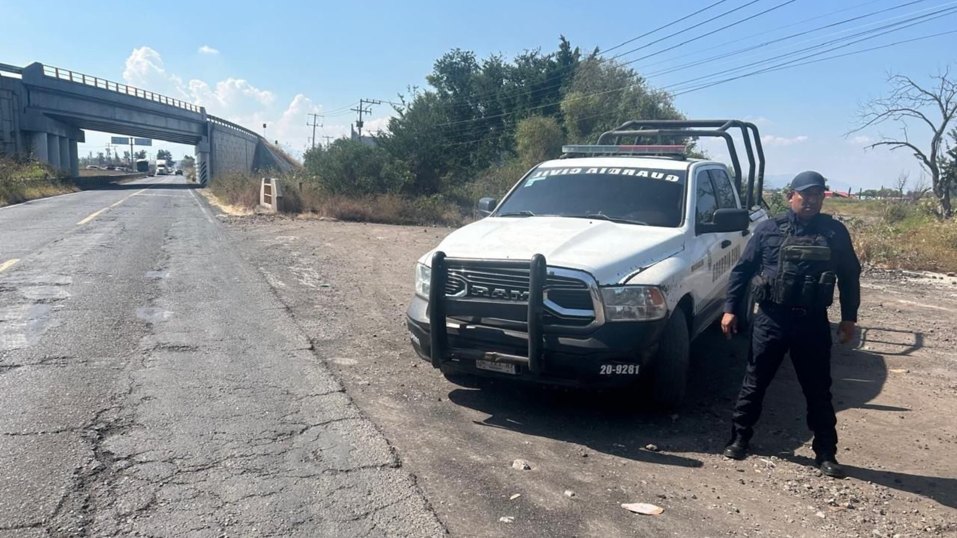 Un policía al lado de una carro.