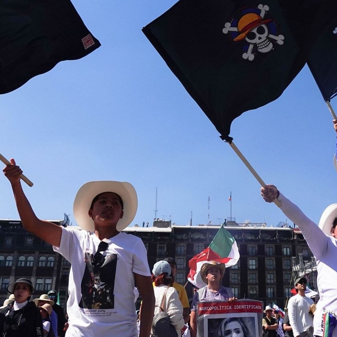 Tres personas alzan banderas negras.