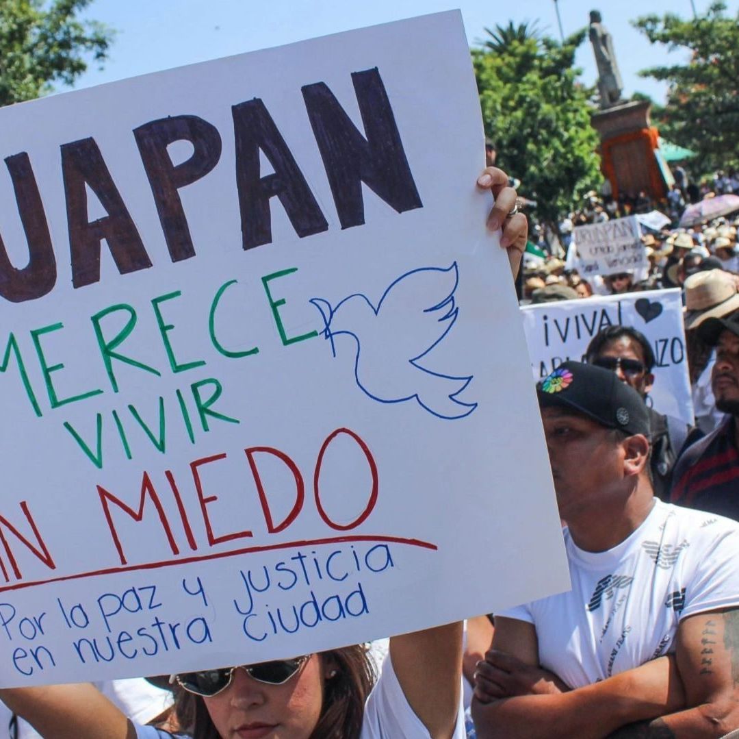 Un grupo de personas en protestas cargan un cártel.