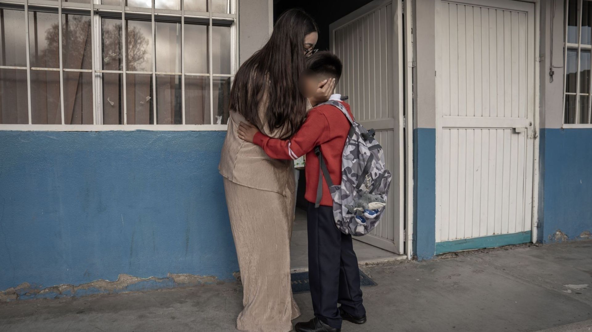 Una mamá abraza a un estudiante.