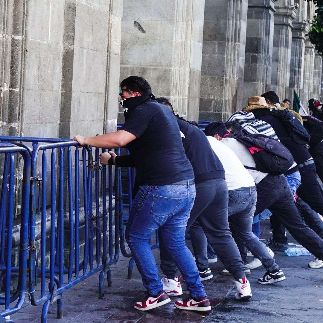 Hombres empujan vallas de metal.