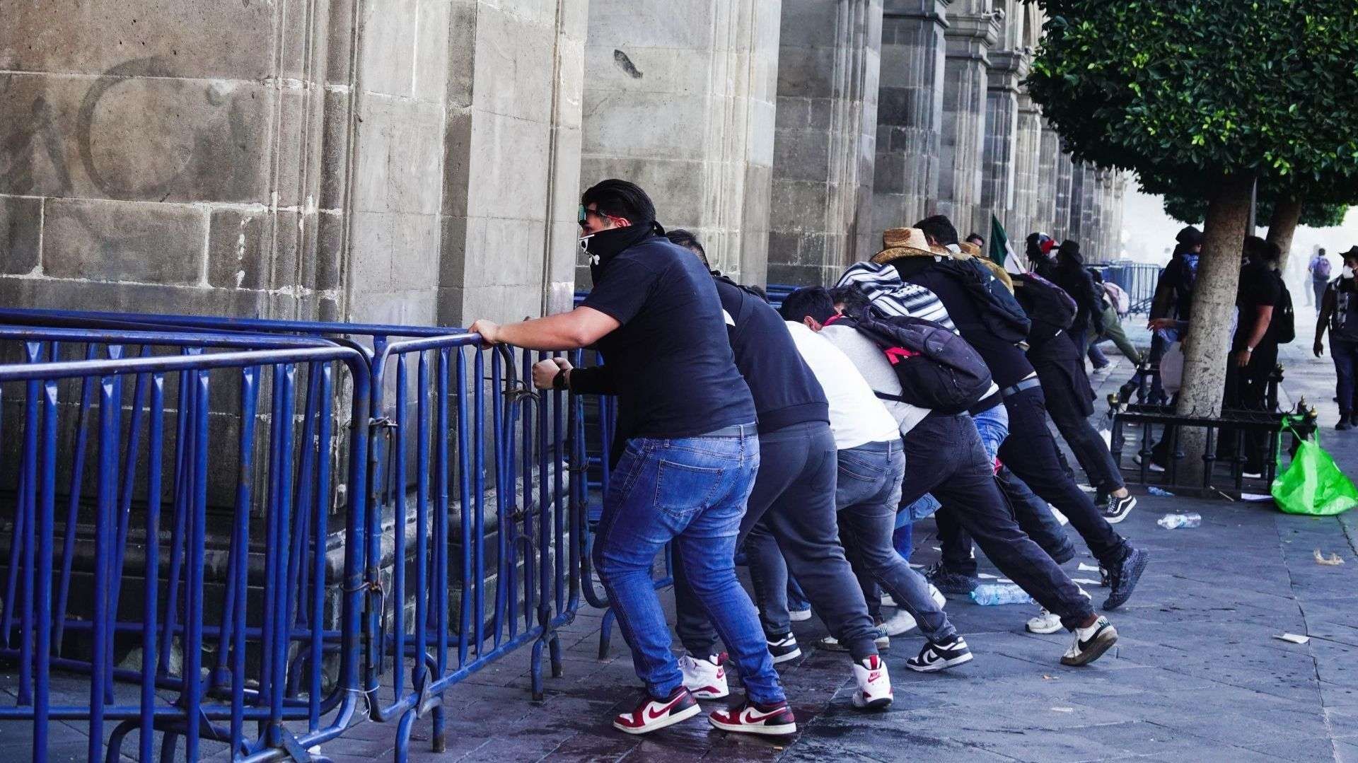 Hombres empujan vallas de metal.