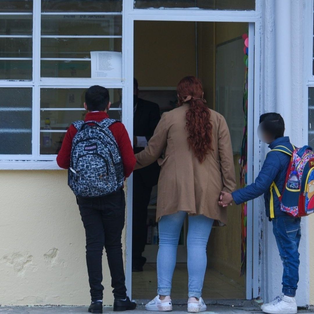 Una mujer sostiene a dos niños de las manos.