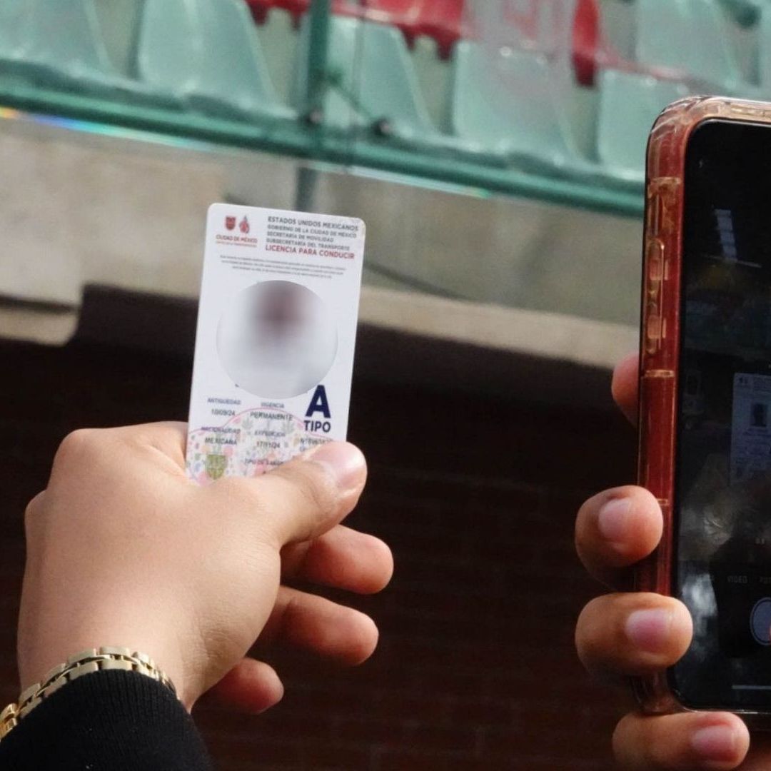 Una persona sostiene su celular y toma una foto de una tarjeta de plástico.