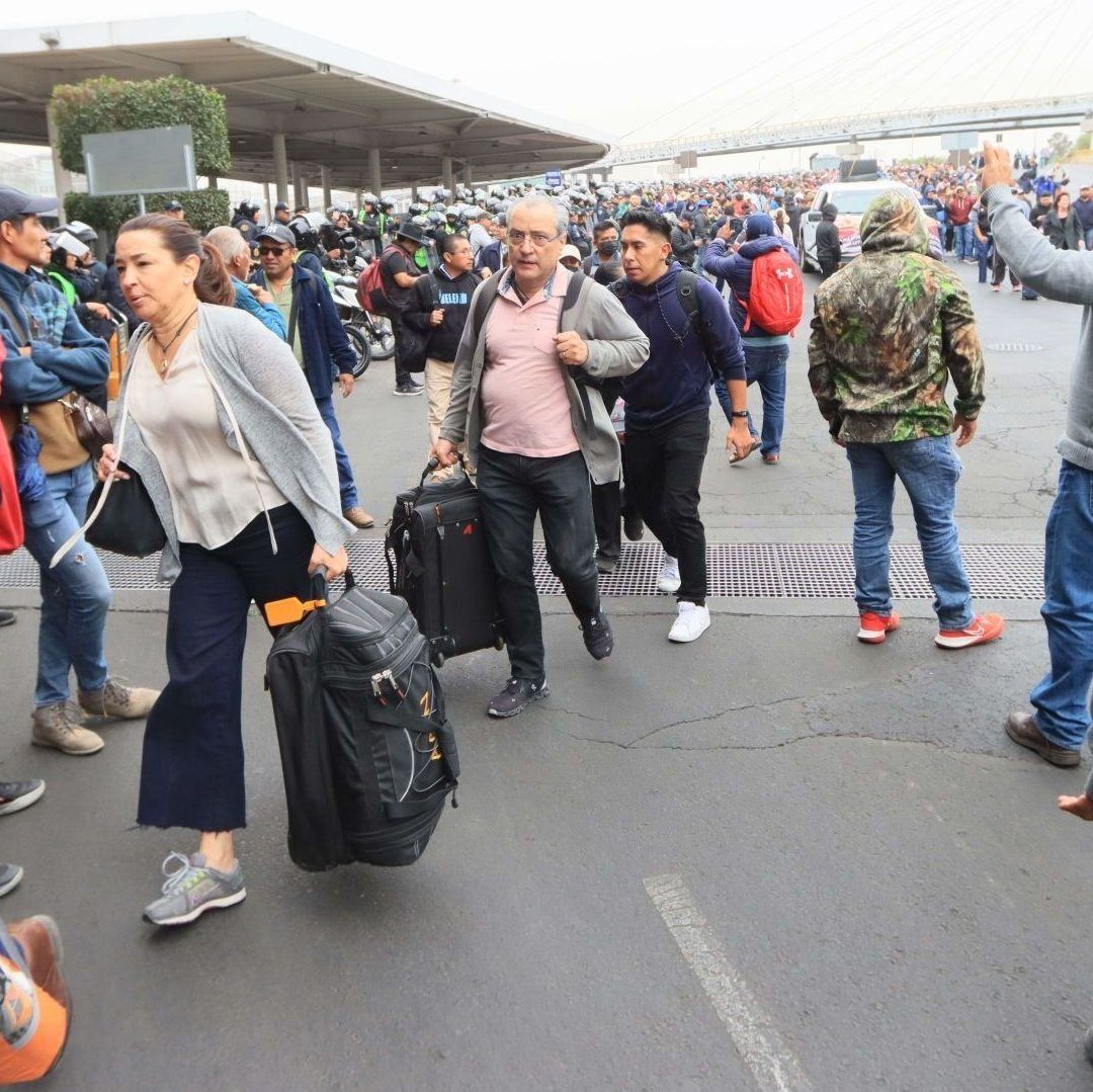 Varias personas aglomeradas cargan maletas.