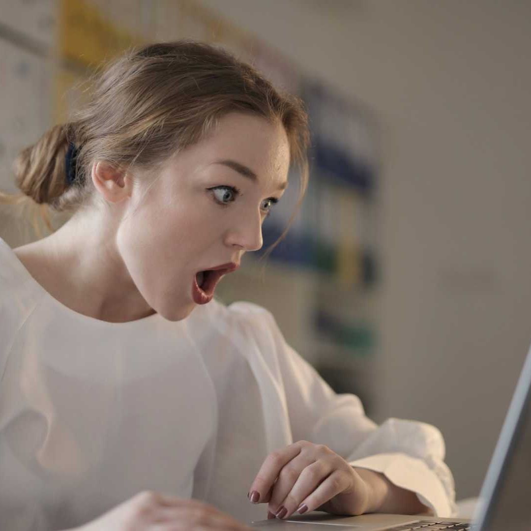 Mujer mira impresionada la pantalla de su computadora