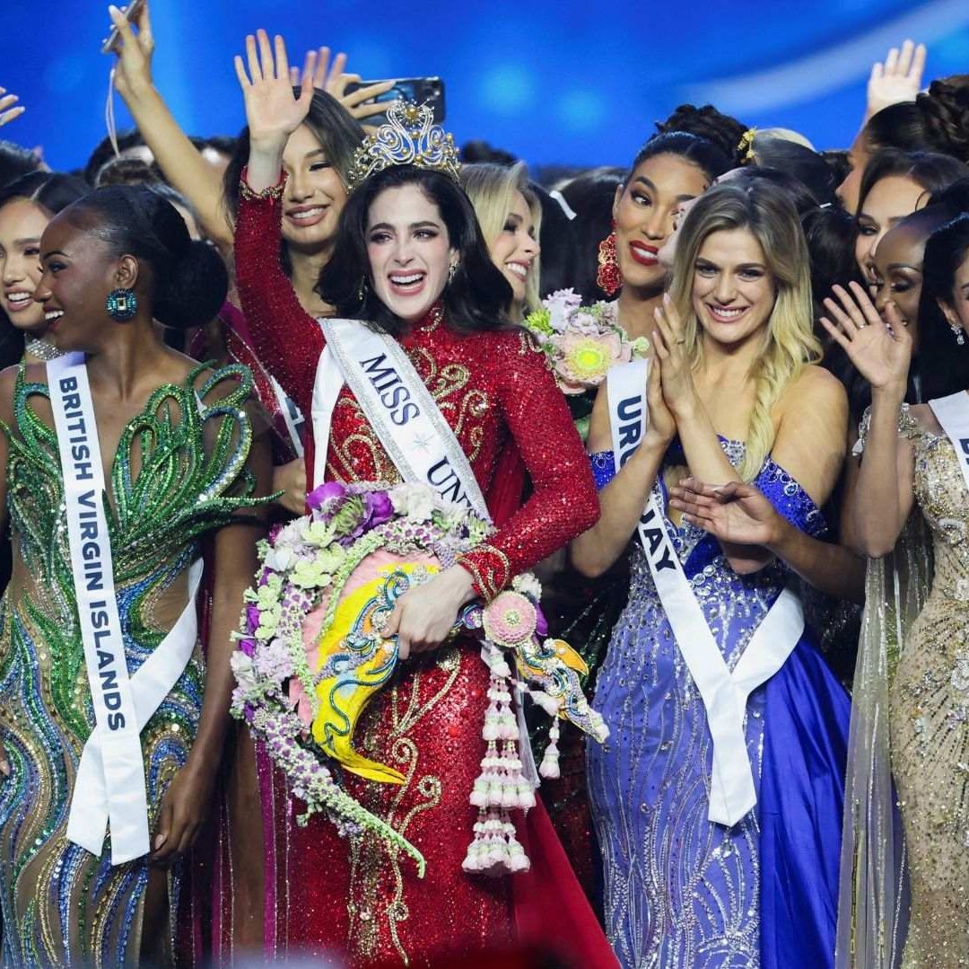 Varias mujeres con vestidos brillantes tienen un semblante de felicidad, una de ellas porta una corona.