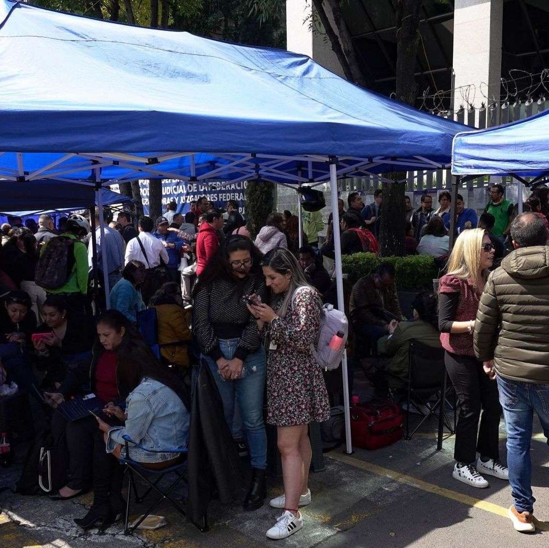 Un grupo de personas debajo de carpas de color azul.