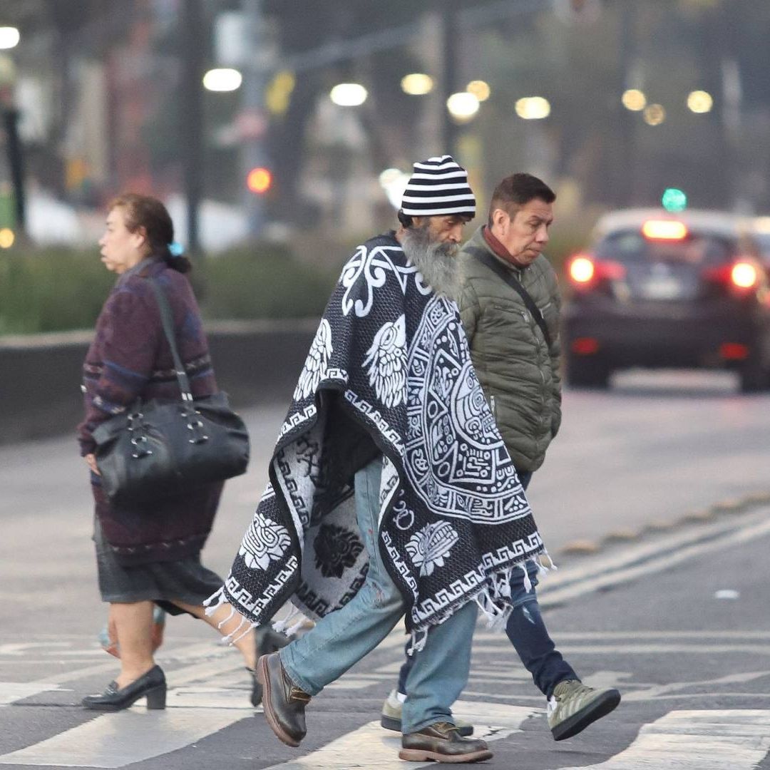 Personas se protegen del frío mientras caminan por calles de la CDMX en enero 2025