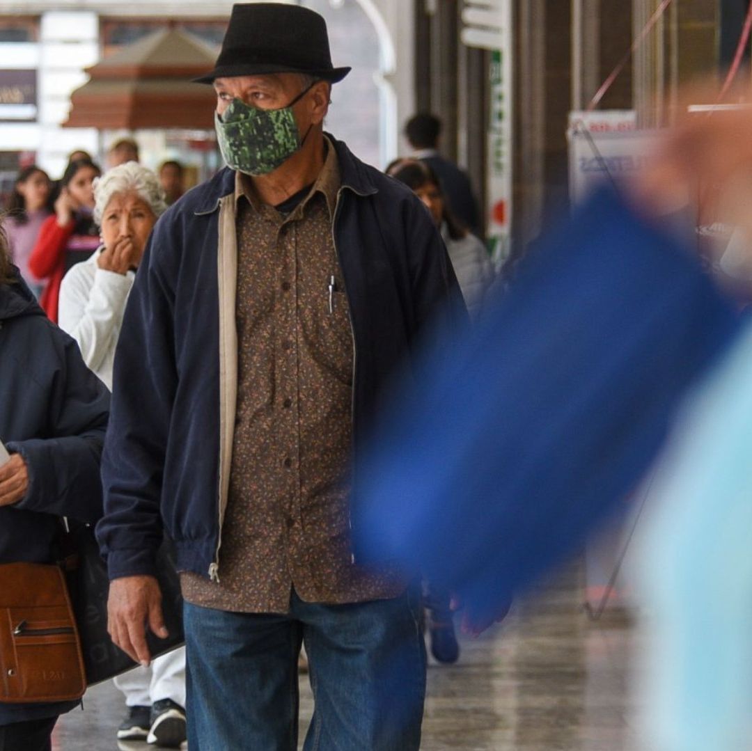 Personas caminando usan cubrebocas.