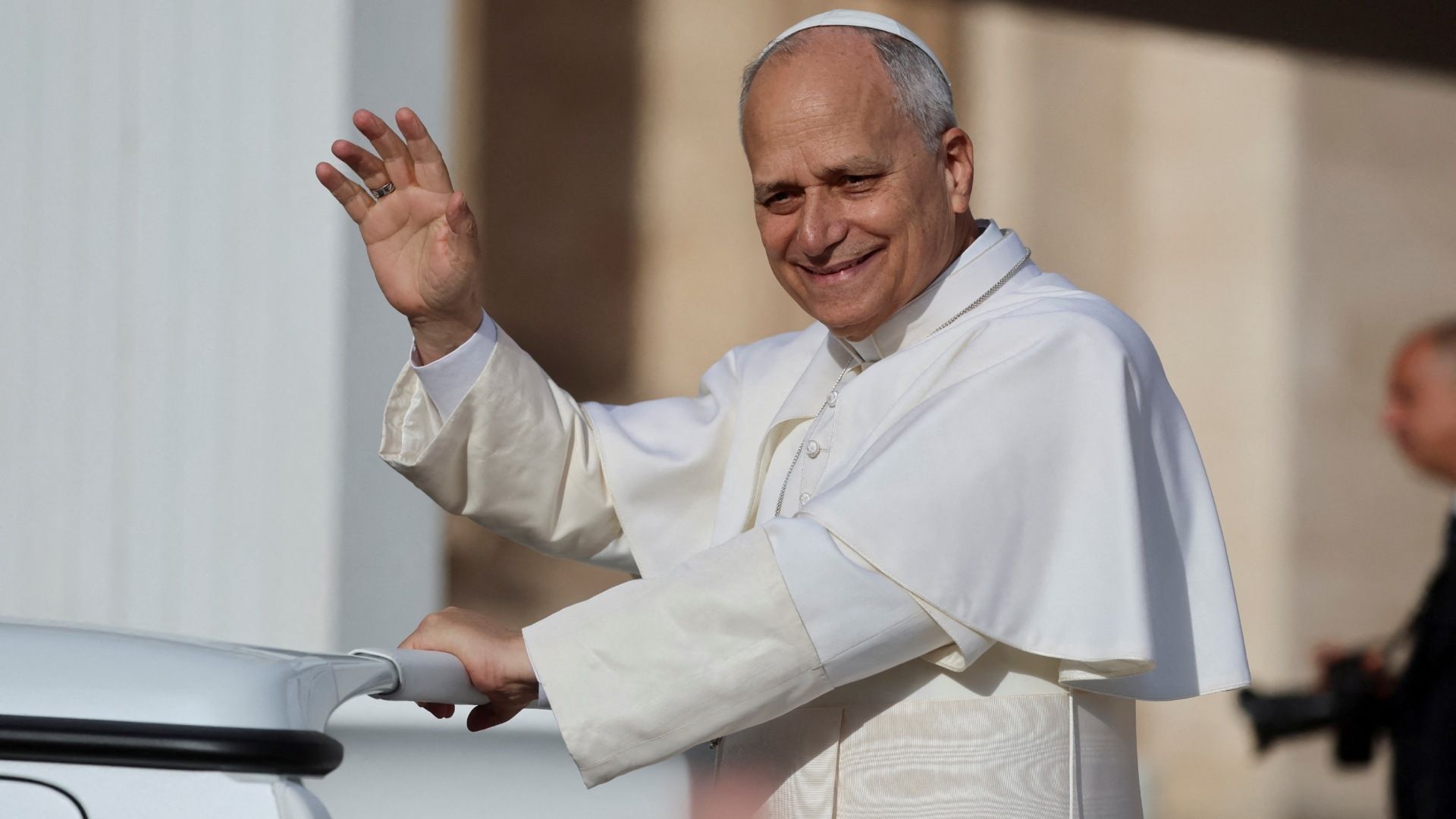 El papa León XIV saluda y sonríe arriba del papamóvil