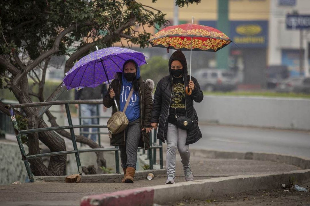 Personas caminan bajo la lluvia