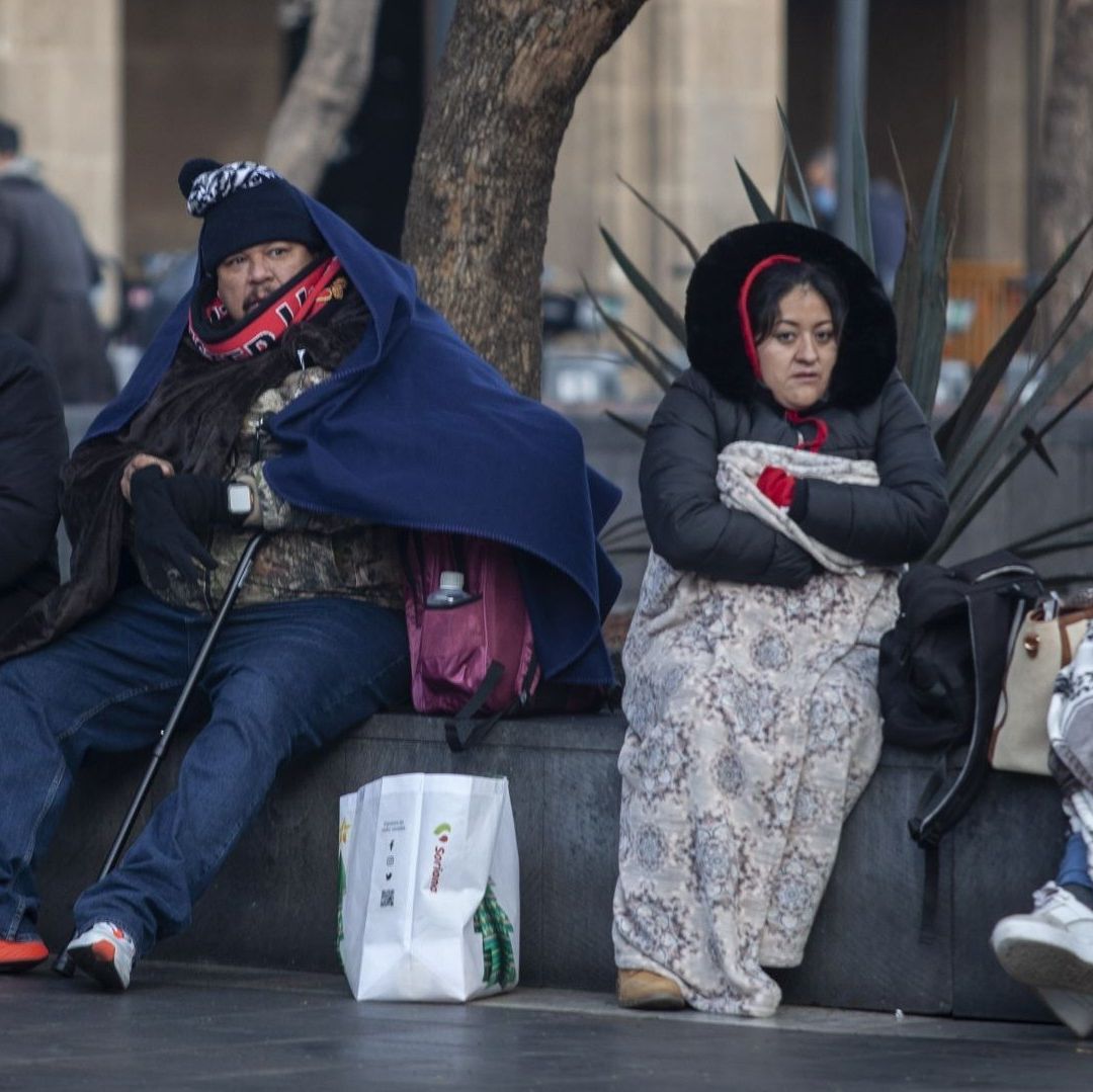 Personas abrigadas están sentadas cubiertas del frío.