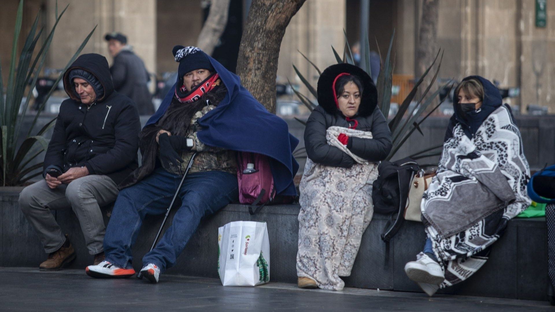 Personas abrigadas están sentadas cubiertas del frío.