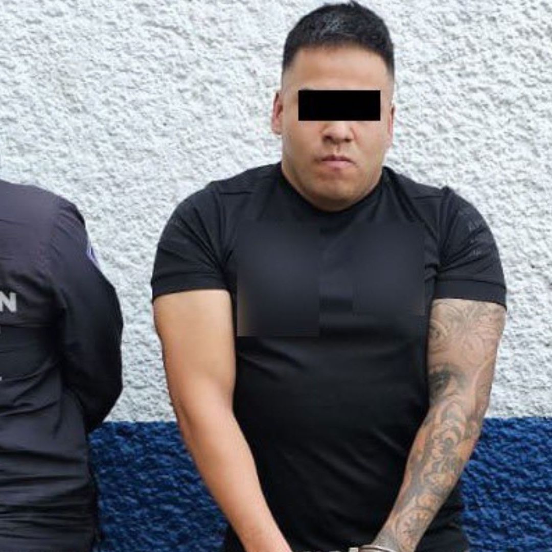 Un hombre con los ojos tapados con cinta negra, es resguardado por dos policías.