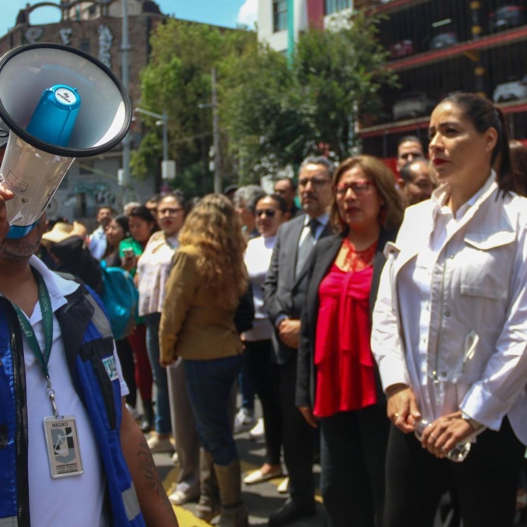 Una persona sostiene un megáfono y alrededor hay varias en un ejercicio de simulacro.