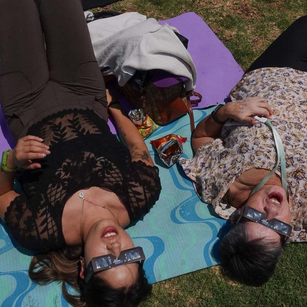 Dos mujeres observan un eclipse solar total.