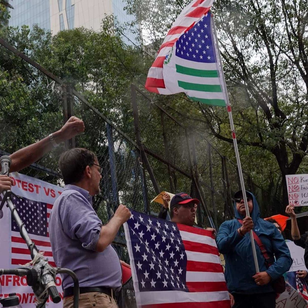 Personas en una marcha portan banderas de México y Estados Unidos.