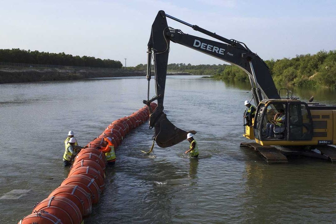 Trabajadores alinean el muro de boyas en Texas, EUA, el 11 de agosto de 2023