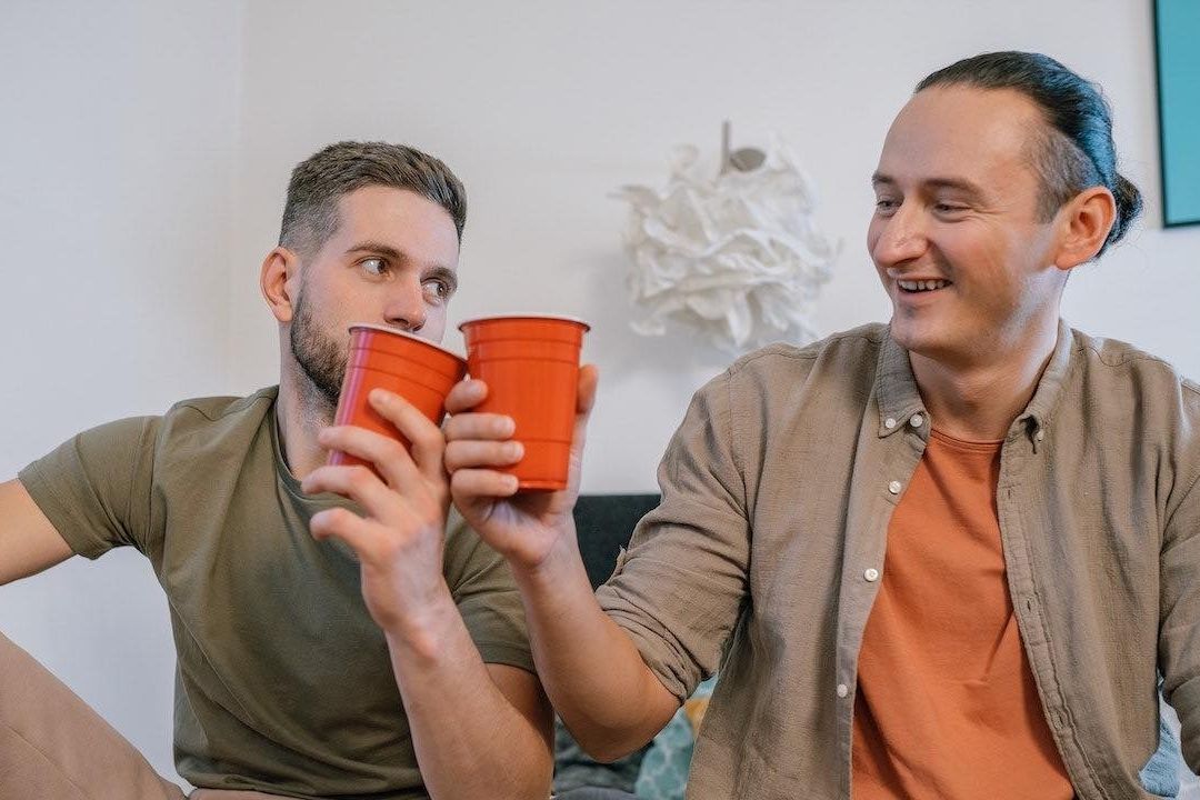 Dos amigos brindan en vasos de plástico
