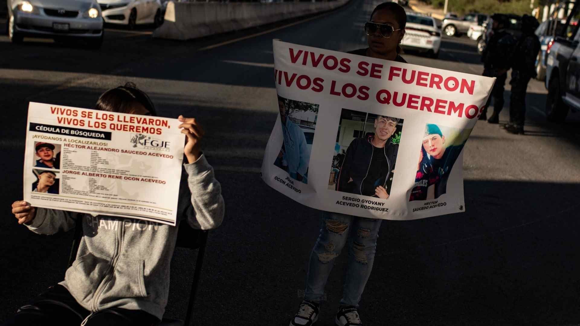 Familiares portan cárteles con las fichas de búsqueda de los jóvenes