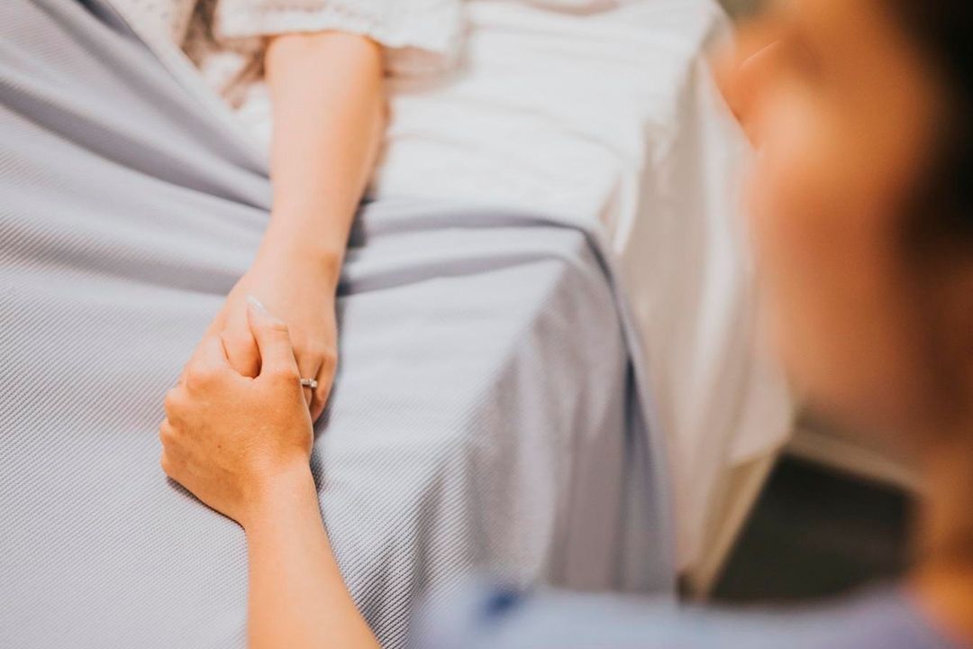 Una cuidadora sosteniendo la mano de un paciente, reflejando la compasión y confianza de las cuidadoras.