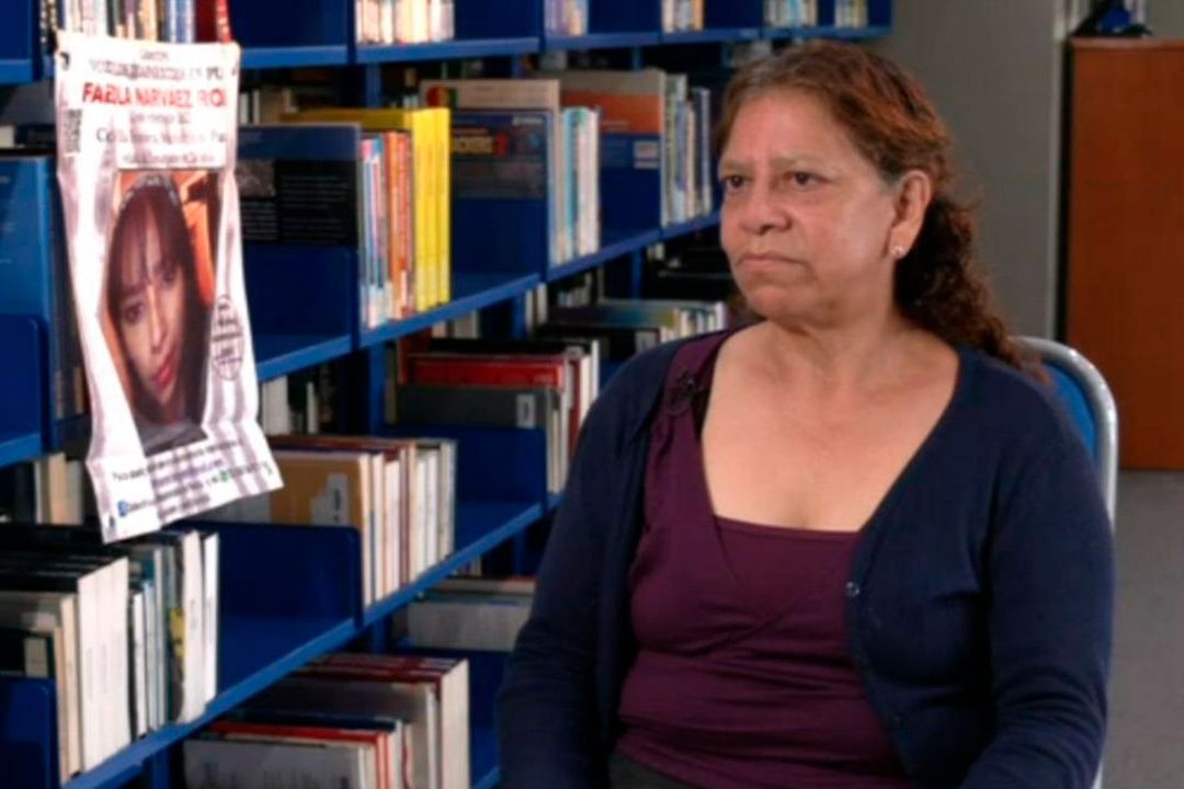 María Eugenia Rojas sosteniendo una foto de su hija desaparecida, Fabiola Narváez, con un fondo del edificio del IMSS.