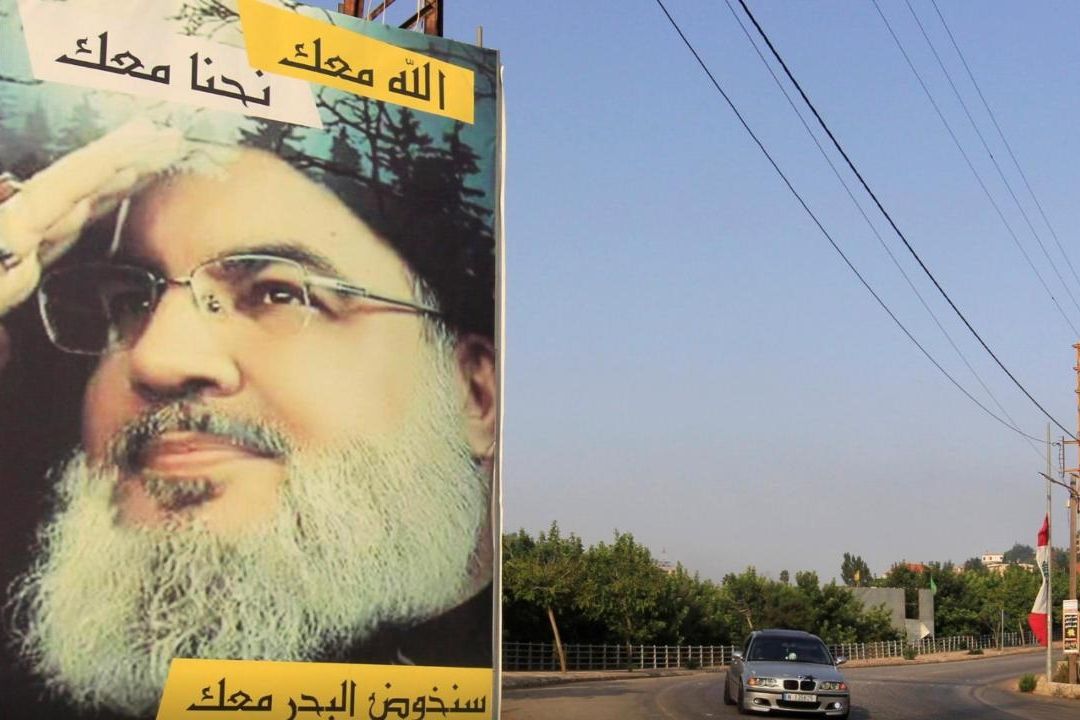 Un automóvil pasa junto a un cartel que muestra al líder de Hezbolá, en Líbano, Sayyed Hassan Nasrallah