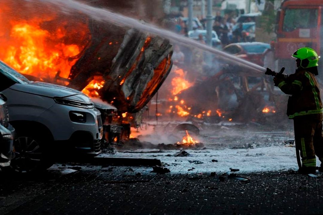 Bombero sofocando fuego en autos estacionados.