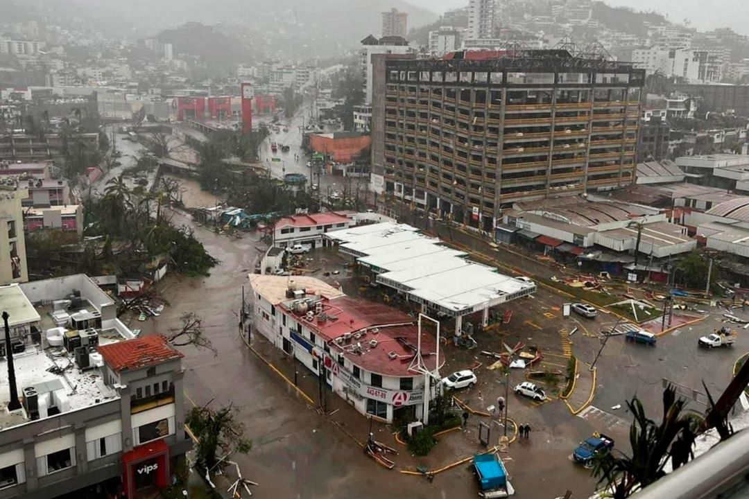 Acapulco inundado: edificios dañados, vehículos dispersos, árboles caídos y calles desoladas.