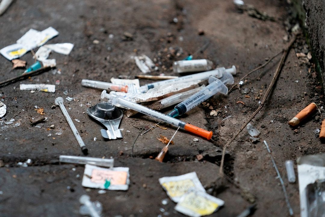 Basura en el suelo: jeringas usadas, colillas y envoltorios rotos.