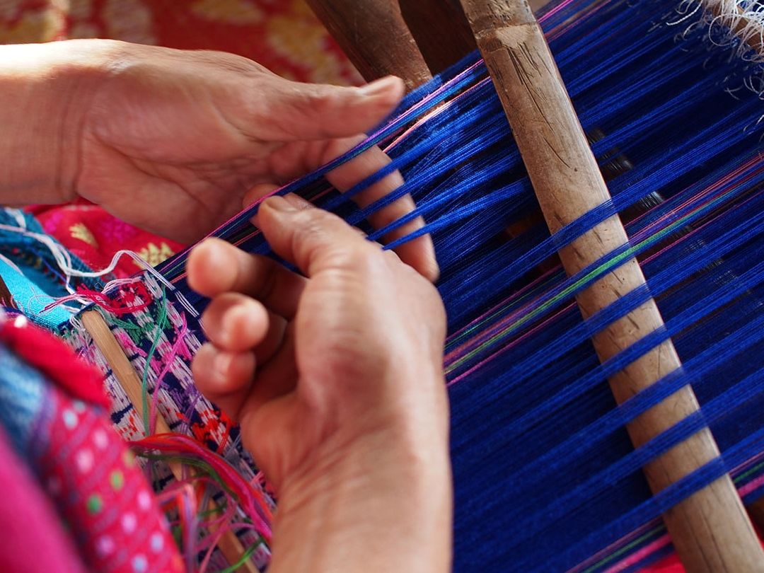 Artesana tejiendo tela vibrante en telar manual tradicional